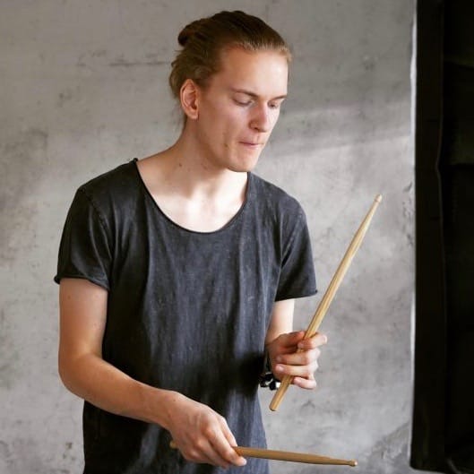 a boy playing electronic drums with sticks in his hands